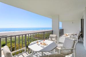 卡纳维拉尔角Cape Winds的一个带桌椅和海滩的阳台
