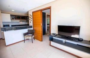 卡姆布库Manacá Apartamentos , Kariri Beach , Cumbuco的带电视的客厅和厨房