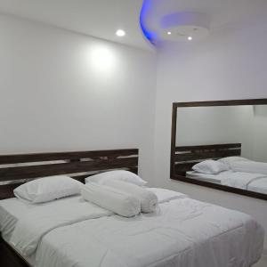DukuBudi Asih Guest house Syariah的一间卧室配有两张白色的床和镜子