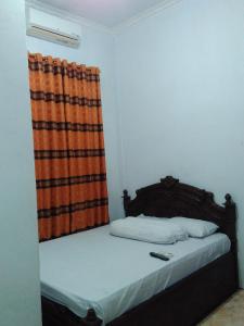 BaubauWisma Kahyangan的一间卧室配有一张带橙色窗帘的床