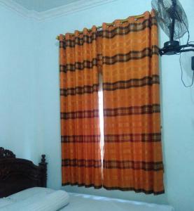 BaubauWisma Kahyangan的床上的窗帘和风扇