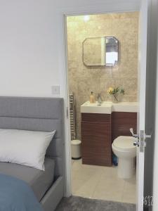 诺丁汉Flat 2 - Entire Modern Two Bedrooms home with en-suite & free parking close to QMC, City centre and Notts uni - Self check in的浴室设有床、水槽和镜子