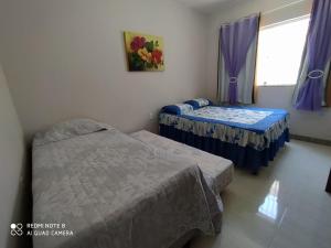 古里里Casa de Praia Lado Sul的紫色窗帘和窗户的客房内的两张床