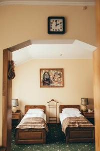 赫梅利尼茨基Lyube的一间卧室设有两张床,墙上挂着一个时钟。