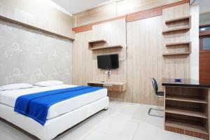 万隆Hotel Bandung Permai的一间卧室配有一张床、一张书桌和一台电视。