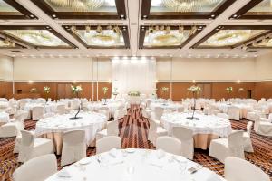 钏路钏路全日空皇冠假日酒店的宴会厅配有白色的桌椅和吊灯