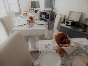 莱万托城堡之下住宿加早餐旅馆的一间用餐室,配有白色的桌椅和一盒面包