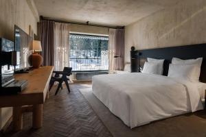 巴库里阿尼Rooms Hotel Kokhta的一间卧室配有一张大床、一张书桌和一个窗户。