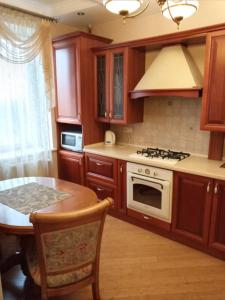 乌日霍罗德1-комнатная квартира ВИП уровня посуточно в Ужгороде. ул.И.Франка.的厨房配有木制橱柜、桌子和炉灶。