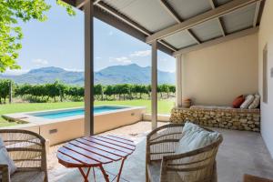 弗朗斯胡克La Chataigne Wines & Guest Cottages的一个带桌椅的庭院和一个游泳池