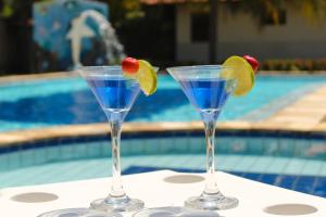 马拉戈日Village Miramar的两个马提尼玻璃杯,在游泳池畔的桌子上放水果