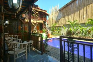 坎古Tropical Canggu Hostel的一座带游泳池和椅子的度假村,毗邻一座建筑