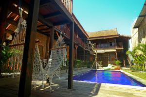 坎古Tropical Canggu Hostel的房屋前设有带秋千的天井和游泳池。