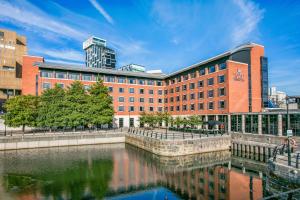 利物浦皇冠假日利物浦市中心酒店的水体旁边的一个大砖砌建筑