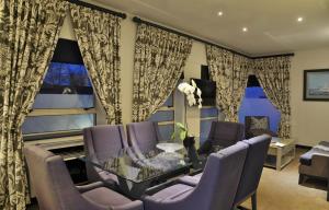 开普敦波茨伍德酒店的客厅配有玻璃桌和紫色椅子