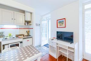 巴约讷Appart'Hôtel Bellevue的一间带白色橱柜的厨房和一张带电视的书桌