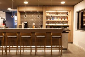辛德尔芬根Holiday Inn Express - Sindelfingen, an IHG Hotel的厨房设有带四把凳子的酒吧