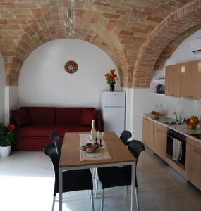 奥菲达Residence Borgo Offida的厨房以及带桌子和红色沙发的客厅。