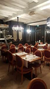 卡布尔Hôtel La Champagne Ardenne Cabourg的一间带桌椅和吊灯的用餐室