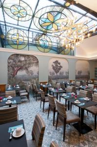 巴黎Hôtel Saint-Pétersbourg Opéra & Spa的一间带桌椅的用餐室和彩色玻璃天花板