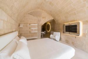 马泰拉Aquatio Cave Luxury Hotel & SPA的卧室配有白色的床和电视