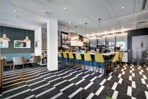 蒙特利尔Hôtel Uville Montréal的餐厅设有格子地板和黄色酒吧凳子