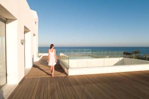 莫纳斯提尔莫纳斯提尔塔拉萨皇家酒店的站在一个眺望海洋的阳台上的女人