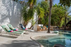 奥奇瓦龙戈Out of Africa Town Lodge的一组椅子和一个棕榈树游泳池