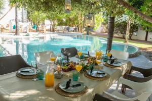 奥奇瓦龙戈Out of Africa Town Lodge的游泳池旁的餐桌,供应食物和饮料