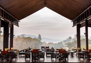 布莱尔港Symphony Samudra Beachside Jungle Resort And Spa的餐厅设有桌椅和大窗户。