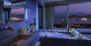 伊斯坦布尔马尔马拉佩拉酒店的大型浴室设有大浴缸和窗户。