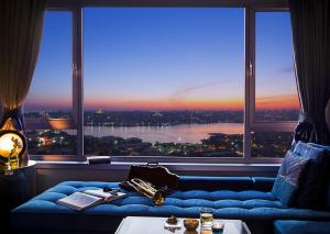 伊斯坦布尔马尔马拉佩拉酒店的一间位于大窗户前的蓝色沙发客房