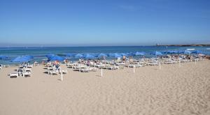 奇尼斯TH Cinisi - Florio Park Hotel的海滩上的一组椅子和遮阳伞