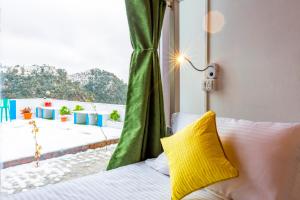 穆克缇斯瓦Zostel Mukteshwar的窗户间里一张带黄色枕头的床