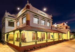 马哈巴利普拉姆Marutham Village Resort的街道上一座黄色的建筑,配有桌椅