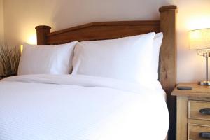 多尔顿因弗内斯The Black Dog Inn的一张带白色枕头和木制床头板的床