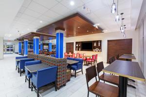 塔尔萨Holiday Inn Express & Suites Tulsa South - Woodland Hills, an IHG Hotel的一间配备有蓝色桌椅的用餐室