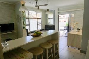 巴利托10 Coral Cove的厨房配有带凳子和一碗水果的柜台