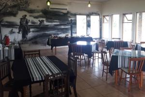亚瓜龙潘帕旅馆的餐厅设有桌椅,墙上挂有绘画作品