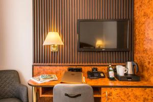 纽伦堡巴多利诺美食酒店的酒店客房配有带笔记本电脑的书桌和电视。