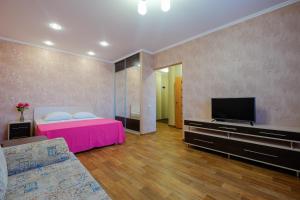 托木斯克ОК! Советская, 60 №1的卧室配有粉红色的床和平面电视。