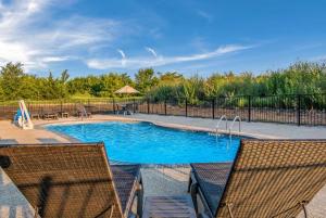 迪索托Comfort Suites DeSoto Dallas South的一个带两把椅子和围栏的游泳池