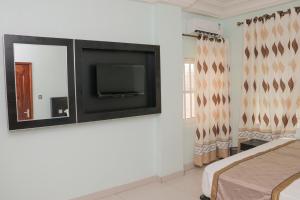 科托努BERACA INN的卧室配有壁挂式平面电视