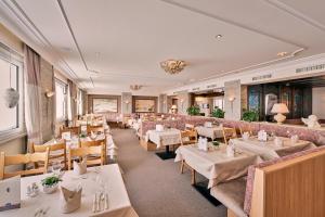 祖尔斯Hotel Enzian的一间设有白色桌椅的用餐室
