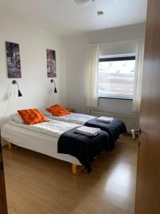 格仑达积图Kirkjufell Guesthouse and Apartments的一间卧室配有两张带橙色枕头的床和窗户。