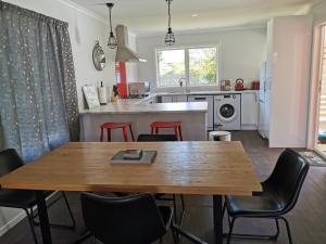 凯里凯里Kerikeri Sunny Modern 2 Bedroom Apartments的厨房以及带木桌和椅子的用餐室。