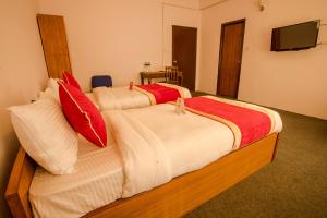 加德满都135迷失花园公寓OYO房山林小屋的一间卧室配有两张带红白色枕头的床