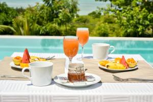 ChanjaniThe Palm Residence by Amazing Zanzibar的一张桌子,上面放着两杯果汁和水果盘