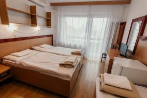 塞格德蒂萨体育酒店的一间卧室设有两张床、一张桌子和一个窗口。
