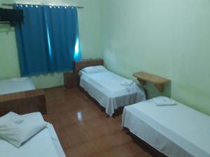 吉巴拉那Hotel Chalé Ji-Parana的带三张床和蓝色窗帘的房间